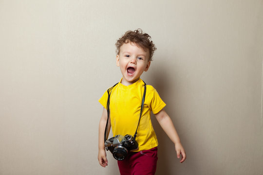 little boy on a grey wall taking a photo using a vintage camera