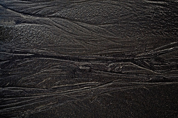 black wet sand from above after low tide in the ocean