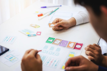 Designer creative graphic discussing sketch planning application mobile phone in office. User experience concept.