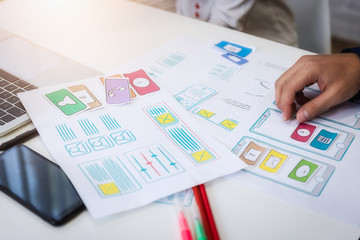 Closeup hand of graphic designer working about wireframe application designe in office. User...