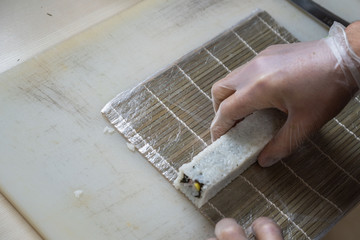 Cook hands making japanese sushi roll. Japanese chef at work preparing delicious sushi roll with eel and avocado. Appetizing japanese food.