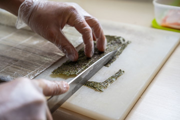 Cook hands making japanese sushi roll. Japanese chef at work preparing delicious sushi roll with eel and avocado. Appetizing japanese food.