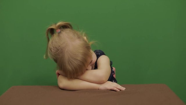 Girl sitting at the table. She is tired and yawn. Happy three years old girl. Cute girl smiling. Brown eyes. Pretty little child, 3-4 year old blonde girl. Make faces. Green screen video. Chroma Key