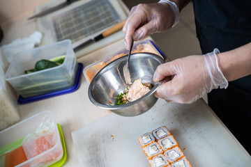 Cook hands making japanese sushi roll. Japanese chef at work preparing delicious sushi roll with eel and avocado. Appetizing japanese food.