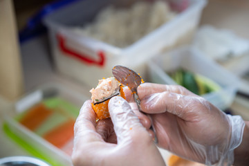 Cook hands making japanese sushi roll. Japanese chef at work preparing delicious sushi roll with eel and avocado. Appetizing japanese food.