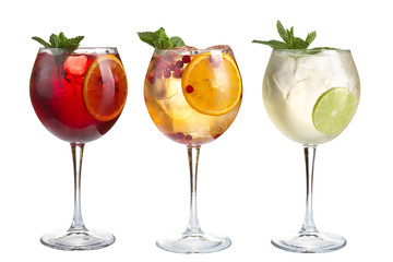 Alcoholic and non-alcoholic refreshing cocktails with mint, fruits and berries on a white background. Three cocktails in glass glasses on a long leg.