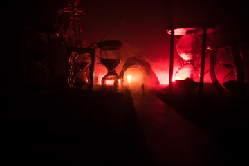 Time concept. Silhouette of a man standing between hourglasses with smoke and lights on a dark background. Surreal decorated picture