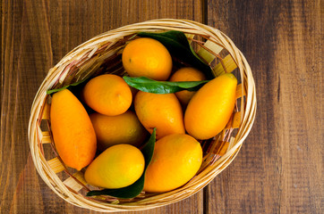 Ripe sweet orange kumquats fortunella in wooden basket.