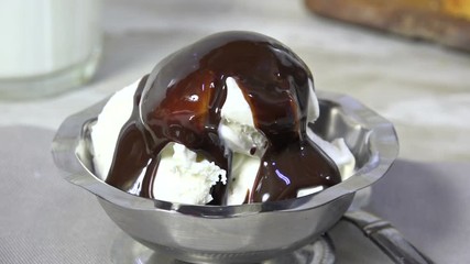 Pouring chocolate syrup on a glass of ice cream