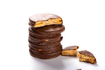 chocolate outer biscuits stacked up with one piece broken on white background