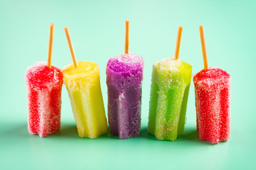 side view multi-color popsicles line up on green background