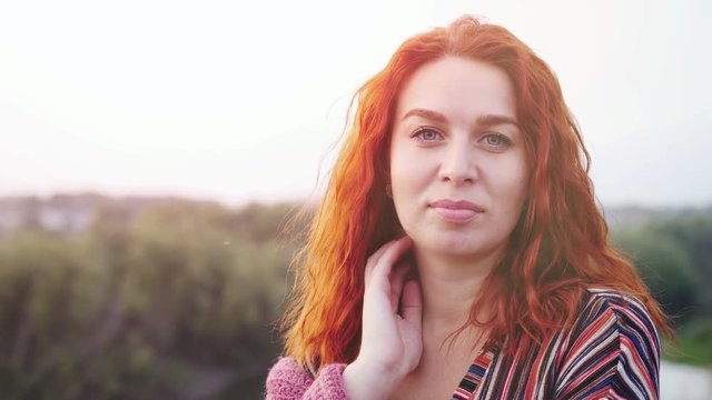Beautiful red haired young woman posing in field at sunset. slow motion. 3840x2160
