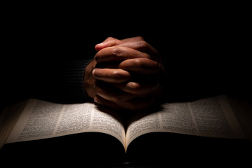 African American Man Praying with Hands on Top of the Bible. - obrazy, fototapety, plakaty