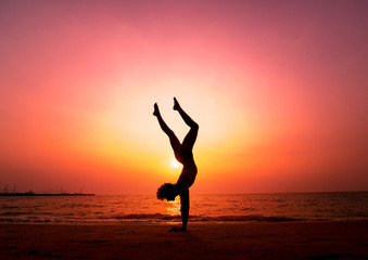 Beautiful young woman practic yoga at the beach. Early morning exercise. Sunrise