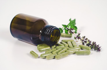 Alternative herb capsule spill out of bottle ,health concept.