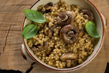 Bowl of pasta with roasted mushrooms, above view on a rustic wooden background, close-up