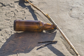 Brown glass bottle  on the beach.  A brown glass bottle in the sand. litter on the beach