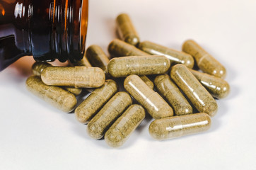 Alternative herb capsule spill out of bottle ,health concept.