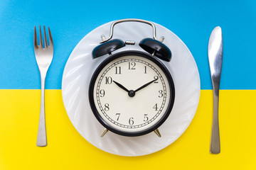 Alarm clock with fork and knife on the table. Time to eat, Breakfast, Lunch time and dinner concept.