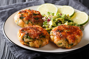 Recipe fried salmon patties with fresh avocado salsa and lime closeup on a plate. horizontal