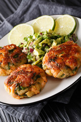 Freshly made salmon burgers with avocado salsa and lime close-up on a plate. vertical