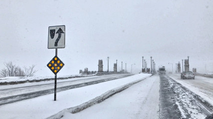 Approach to bridge over the Mississippi River on snowy streets with light traffic during a snow...