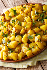 Delicious Indian potatoes Jeera Aloo with spices close-up on a plate. vertical