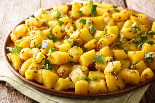 Jeera Aloo boiled potatoes tossed in simple masalas and plenty of coarsely crushed roasted cumin seeds close-up on a plate. Horizontal