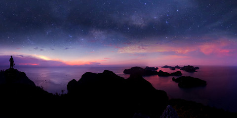 Man standing on the mountain with panorama view and million stars galaxy