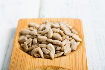 pile of sunflower seeds on bamboo, white wooden table