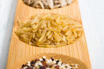 pile of uncooked unpeeled rice on bamboo, white wooden table