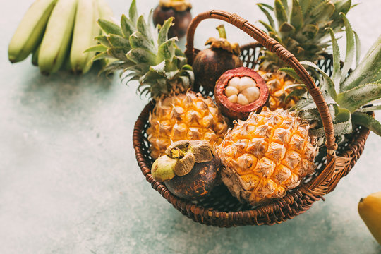 Ripe tropical fruits in a basket, pineapples, mangosteen.