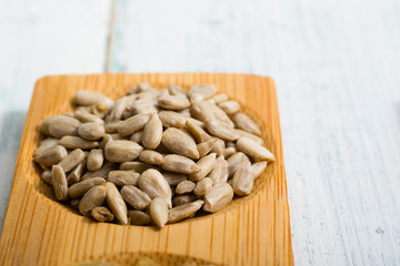 pile of sunflower seeds on bamboo, white wooden table