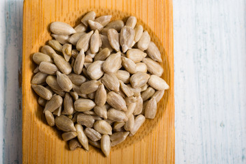 pile of sunflower seeds on bamboo, white wooden table