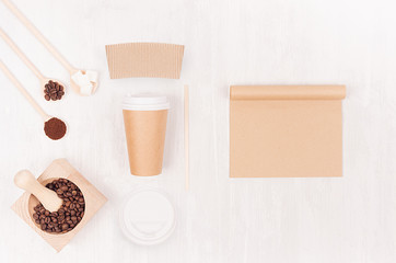 Coffee takeaway set mockup for brand - brown paper cup with blank notebook, label, cap, mortar with coffee beans, sugar on white wood board, top view.