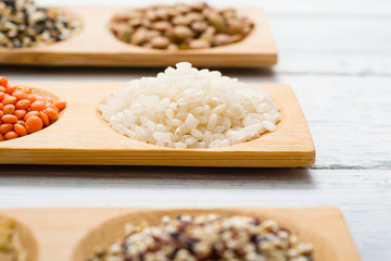 gluten free grains, seeds on bamboo plate, white wood table