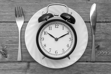 Alarm clock with fork and knife on the table. Time to eat, Breakfast, Lunch time and dinner concept. Black and White Concept
