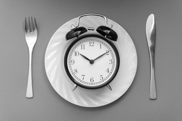 Alarm clock with fork and knife on the table. Time to eat, Breakfast, Lunch time and dinner concept. Black and White Concept