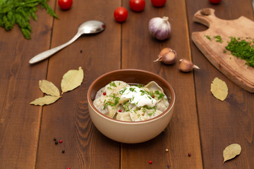 Russian pelmeni meat Dumplings with greens in the plate on wooden table. Tasty homemade meat dumplings.