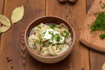 Russian pelmeni meat Dumplings with greens in the plate on wooden table. Tasty homemade meat dumplings.
