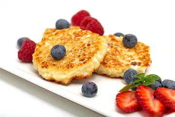 Cheesecakes from cottage cheese with raspberries, strawberries and blueberries. Healthy organic summer dessert cheesecake.