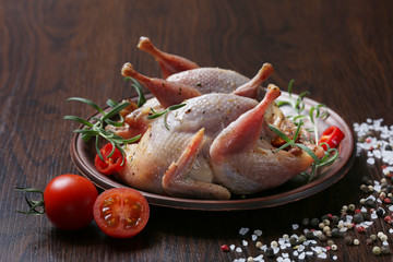 Raw quails ready for cooking on ceramic plate with spices
