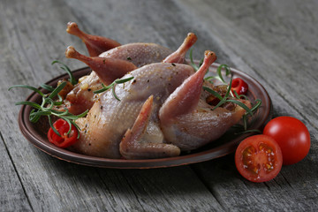 Raw quails ready for cooking on ceramic plate with spices