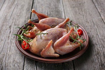 Raw quails ready for cooking on ceramic plate with spices