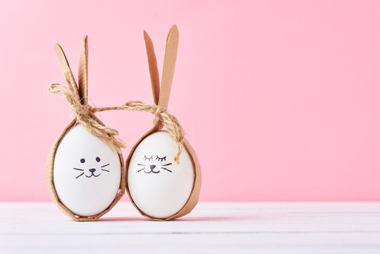 Funny homemade eggs with faces on a pink background. Easter or happy couple concept