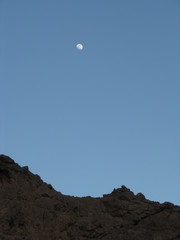 Desierto de Dahab, y luna en cielo azul sobre montañas de Egipto 
