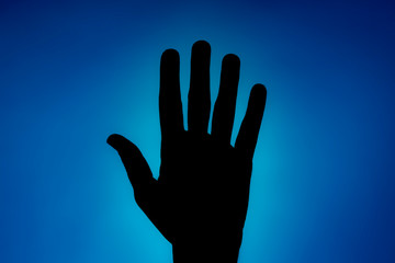 Clean silhouette of a hand against a blue background with a spotlight and bright area right behind it