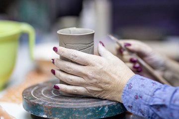 Hands of artist who make a mug from ceramic clay in studio