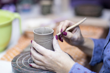 Fototapeta na wymiar Hands of artist who make a mug from ceramic clay in studio