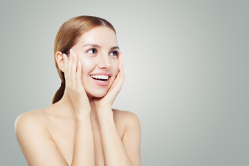 Young surprised woman looking at white background with copy space. Smiling girl portrait